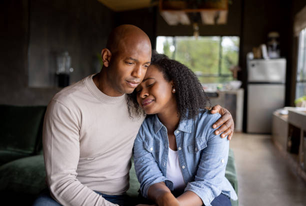 loving husband consoling his sad wife crying at home - women sadness african ethnicity african descent imagens e fotografias de stock