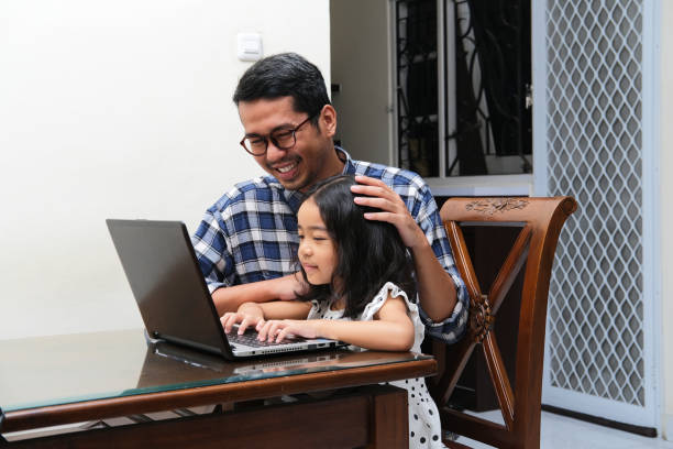 Asian father accompany his daughter when learning something using a laptop Asian father accompany his daughter when learning something using a laptop keluarga stock pictures, royalty-free photos & images