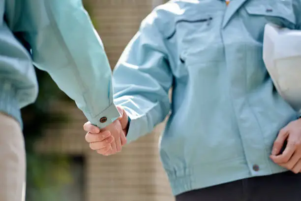 Photo of Construction worker shaking hands in front of the building