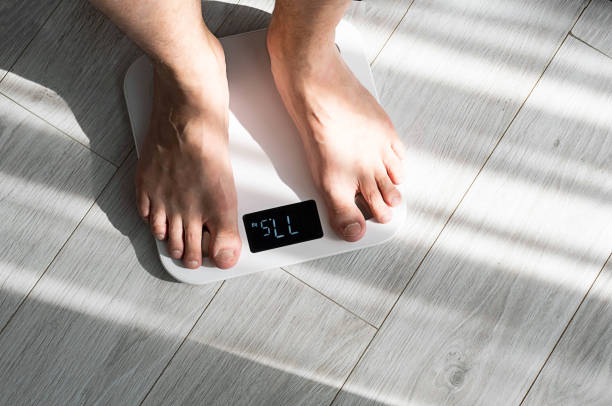 gambe del ragazzo che calpestano le bilance del pavimento a casa. concetto di controllo del peso. - weight scale dieting weight loss foto e immagini stock