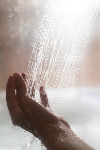 woman holding her hands under the shower