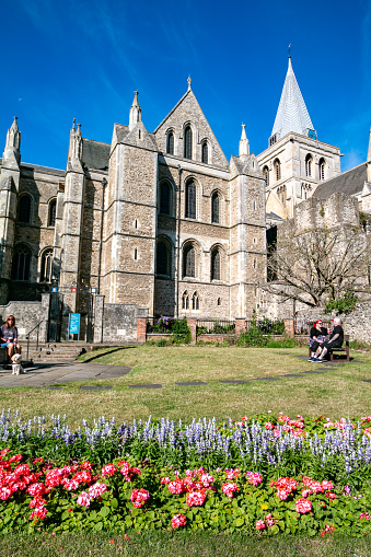People enjoying the sun in a small public park near the war memorial in front of Rochester Cathedral in Kent, England