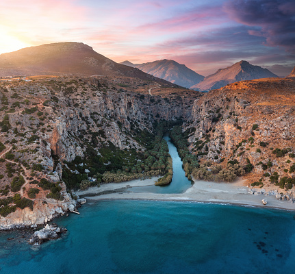 Famous Preveli gorge with river and palm tree forest (South Chania, Crete, Greece). View from the sea at sunset.