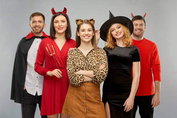 happy friends in halloween costumes over grey friendship, holiday and people concept - group of happy smiling friends in halloween costumes of vampire, devil, witch and leopard over grey background devil costume stock pictures, royalty-free photos & images