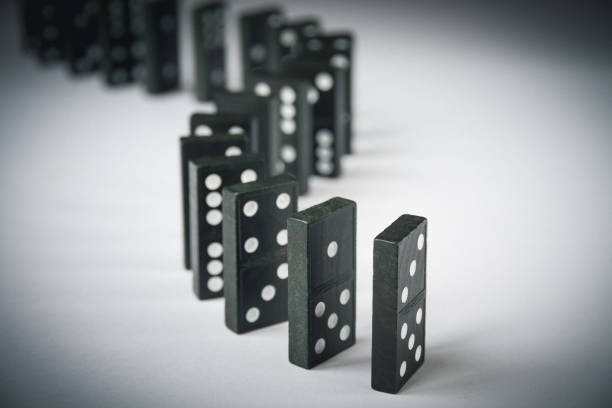 istock Black dominoes chain on white table background 1391165161