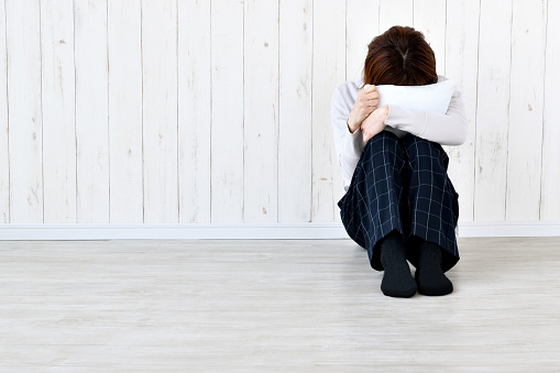 Woman crouching face on cushion in living room