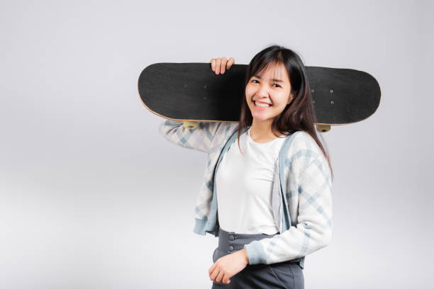istock Smiling happy woman holding skateboard on shoulder 1391167907
