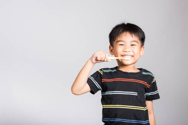 Little cute kid boy 5-6 years old brushing teeth and smile in studio shot isolated stock photo
