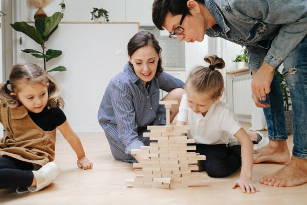 istock Tricky dad blowing on jenga wall, while his son pulling a tile out of it. 1391169620