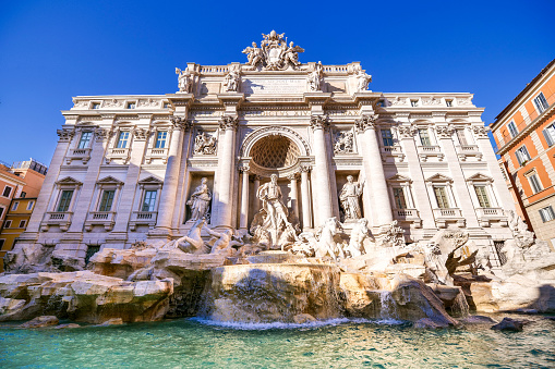 A idyllic and detailed view of the facade of the majestic Trevi Fountain, in the historic and baroque heart of the Eternal City. Built in 1732 on the wishes of Pope Clement XII on the facade of the Palazzo Poli by the architect Nicola Salvi, the Trevi Fountain it's one of the masterpiece of the late Roman Baroque and Neoclassical style, recognized as one of the most beautiful and famous fountain in the world. In the center, the majestic statue of Oceano, made in 1756 by the sculptor Pietro Bacci (1700-1773), with the statues of Health (left) and Abundance (right), both by the artist Filippo Della Valle (1698-1768). In 1980 the historic center of Rome was declared a World Heritage Site by Unesco. Super wide image in high definition format.