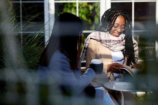 Young women sit in a cafe and spend their free time working and reading.