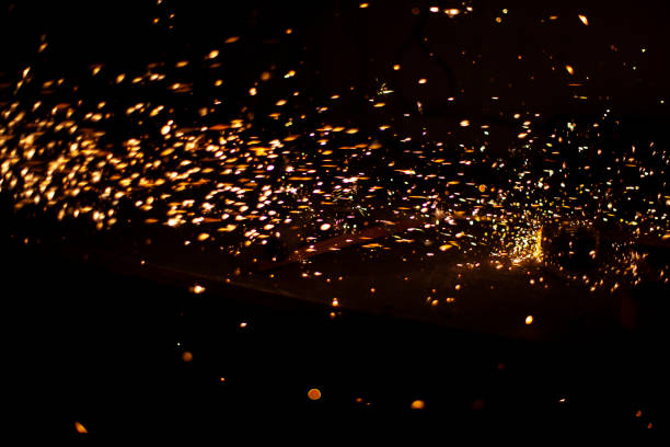 istock Sparks in dark. Flow of sparks from metal processing. Lights on black background. Work in workshop. Grinding steel. Many small particles burn brightly. 1391179855