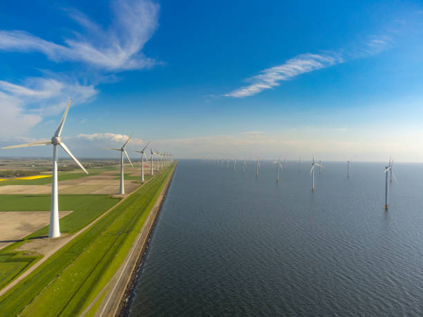 istock Wind turbines on a levee with off shore wind turbines in the background. 1391180370