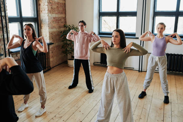 grande gruppo di adolescenti in activewear che si esercitano in un ampio studio loft - vogue dancing foto e immagini stock