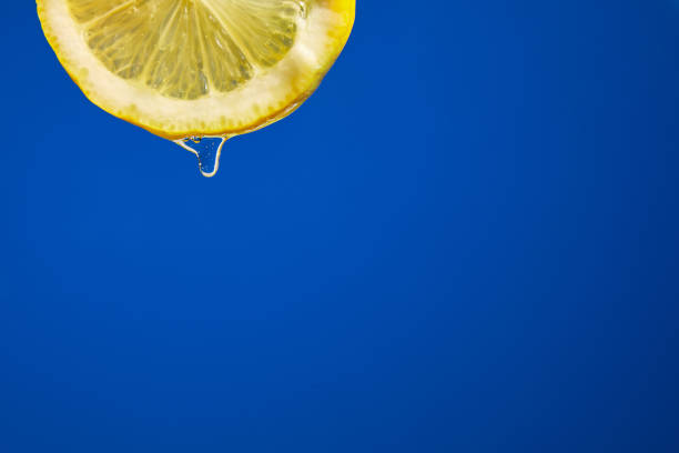 istock Fresh slice of lemon juice drip on blue background, citrus 1391187713