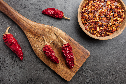 Variety of fresh and dried chili peppers on rustic background