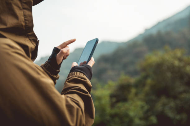 Successful hiker using smartphone on mountain top stock photo