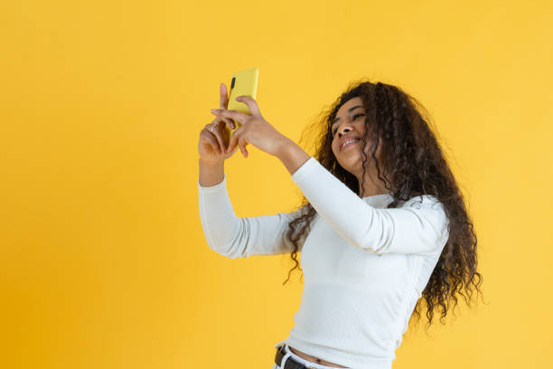 istock Young woman taking selfie on yellow background 1391190740
