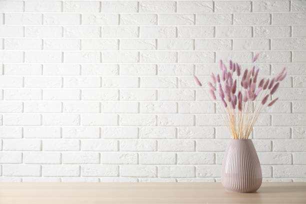 istock Dried flowers in vase on table against white brick wall. Space for text 1391191471