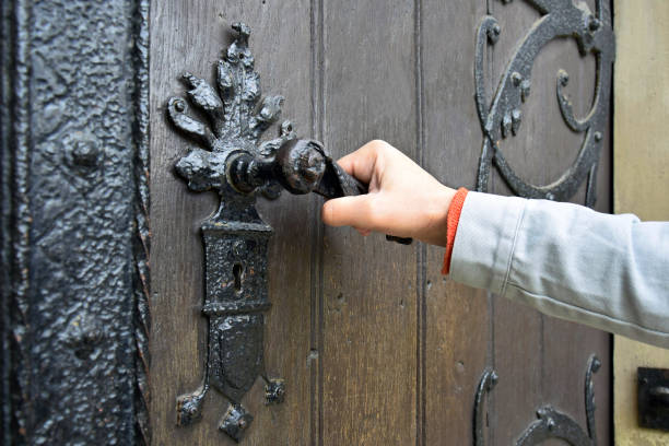istock Man opens an ancient wooden door decorated with wrought iron elements. 1391193355
