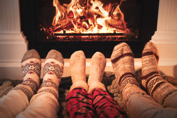 Lovely family in warm socks resting near fireplace at home, closeup Lovely family in warm socks resting near fireplace at home, closeup heat home interior comfortable human foot stock pictures, royalty-free photos & images
