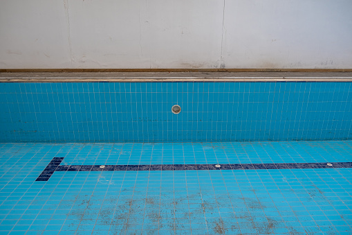 Indoor pool abandoned without care. Blue in color