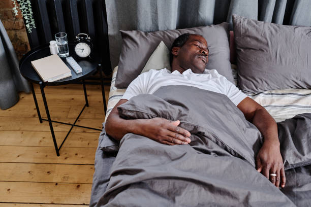 istock Tired senior black man sleeping under grey blanket with his head on pillow 1391199793
