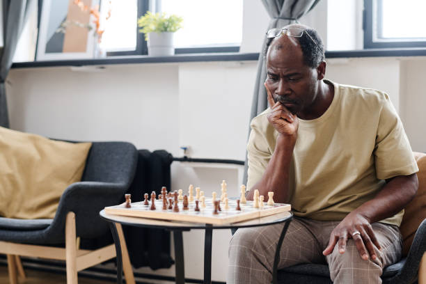 istock Pensive retired man of African ethnicity looking at chess board on small table 1391199938