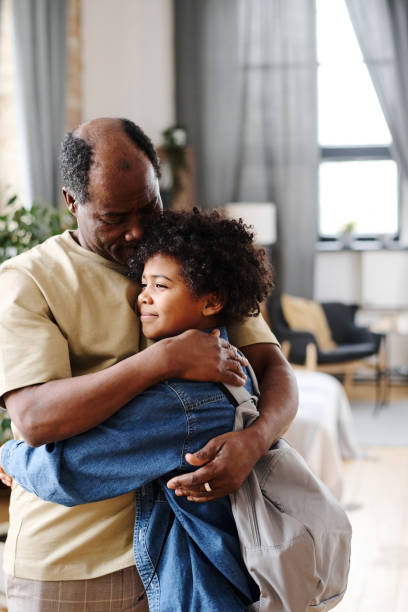 istock Senior black man embracing his cute grandson while seeing him off for school 1391200033