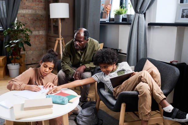 istock Serious grandfather looking at his granddaughter making notes in copybook 1391200068