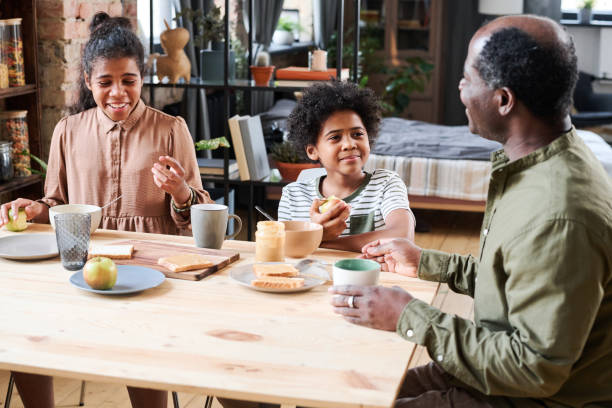 istock Happy cute multi-ethnic schoolkids communicating with grandfather by breakfast 1391200079