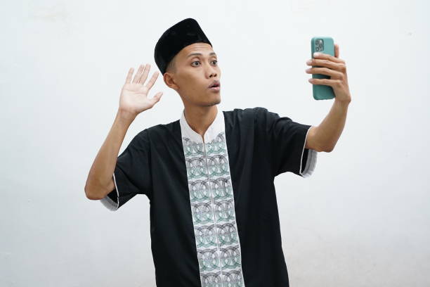 Asian Muslim man showing excited facial expressions during video call with his family during Ramadan / Eid celebrations Asian Muslim man showing excited facial expressions during video call with his family during Ramadan / Eid celebrations keluarga stock pictures, royalty-free photos & images