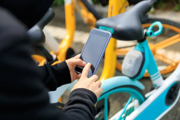 Photo of Hand using smartphone scanning the QR code of shared bike in city