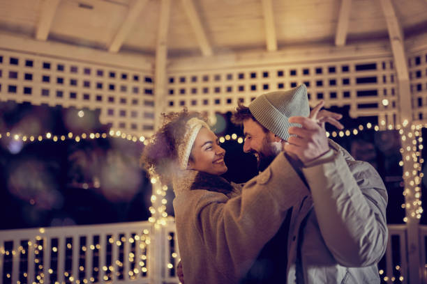 Photo of a couple enjoying the first snow together from their balcony.