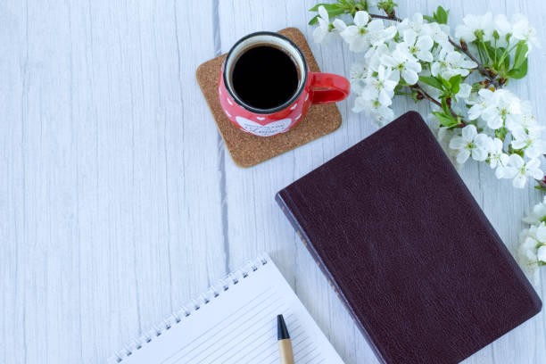 istock Closed Holy Bible Book with a cup of coffee, lined notebook, and flowers on table with copy space 1391206453
