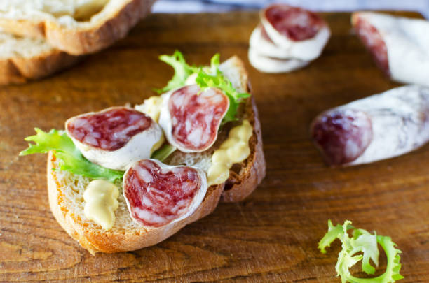 istock Sandwich with Catalan thin sausage with mold - fuet, on a wooden cutting board. Horizontal orientation. 1391207647