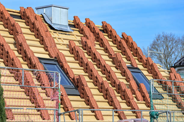 Clay roof tiles stacked on the roof of a residential house in preparation for roofing on a construction site, blue sky stock photo