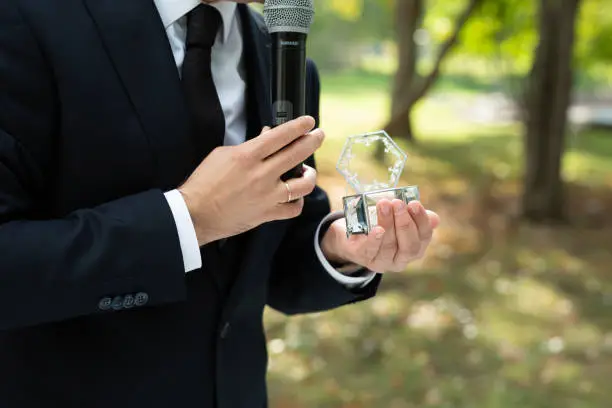 A showman in a classic suit with a microphone at a wedding exit ceremony.