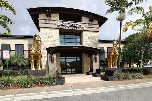 Sunrise, Florida, USA -  March 10, 2022:  Front facade of PF Chang's Restaurant with two giant horses.  PF Chang's specializes in American Chinese cuisine.