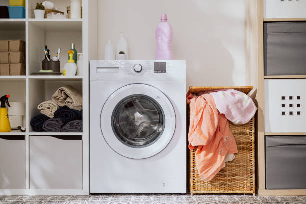istock Washing machine in laundry room with wicker basket for dirty clothes packed full 1391212793