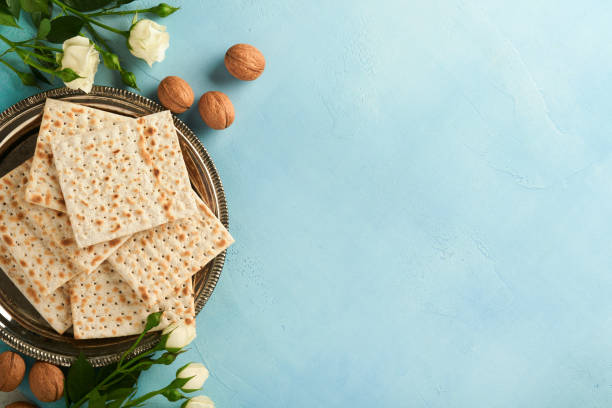 passover celebration concept. matzah, red kosher walnut and spring beautiful rose flowers. traditional ritual jewish bread on light turquoise or blue background. passover food. pesach jewish holiday. - passover imagens e fotografias de stock
