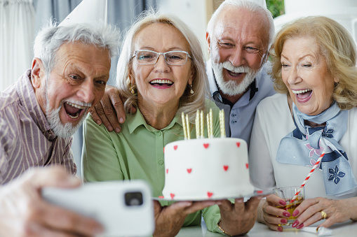 Cheerful senior people having a birthday party. A senior man is taking a selfie at a birthday party