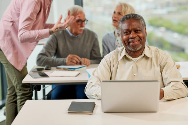 istock A senior african student smiling at the camera while group of multicultural senior students is discussing a programming project with an educator in the classroom. 1391217606