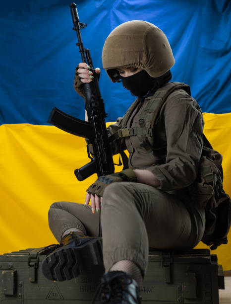 une jeune soldat avec un fusil d’assaut kalachnikov sur le fond du drapeau de l’ukraine - military armed forces patriotism flag photos et images de collection