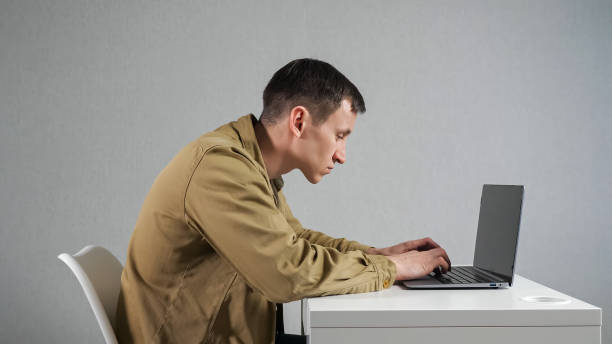 homem empregado com pescoço torto trabalha em laptop no escritório - hump - fotografias e filmes do acervo