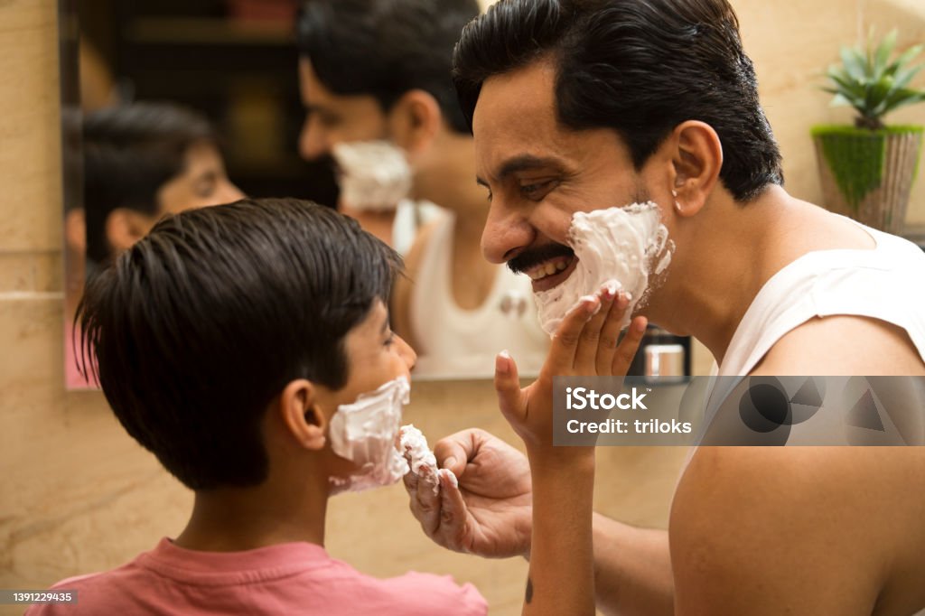 Father and son applying shaving cream on face Father and son having fun applying shaving cream on face of each other in domestic bathroom Shaving Stock Photo
