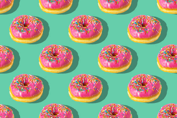 istock Repeating pattern of pink donuts on a green background. Flat lay 1391229469