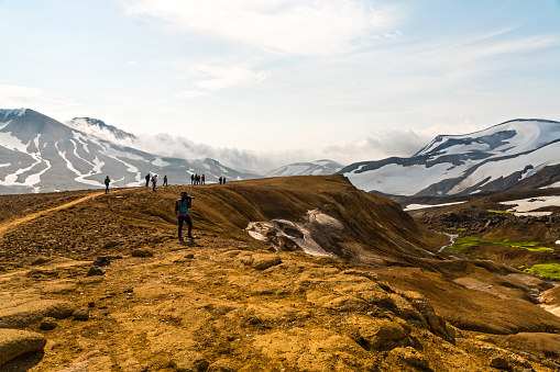 Small group of tourists hiking and photographing from Highlands camping Kerlingarfjoll site to the Hveradalir geothermal area on Kerlingarfjoll mountain range, Iceland.