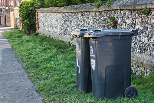 Wheelie bins on a pavement waiting for rubbish collection, UK.