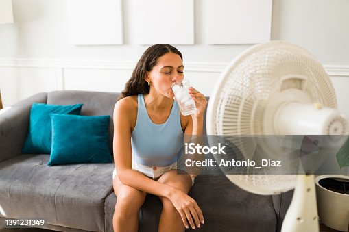 istock Woman enjoying a cold drink in front of the fan 1391231349